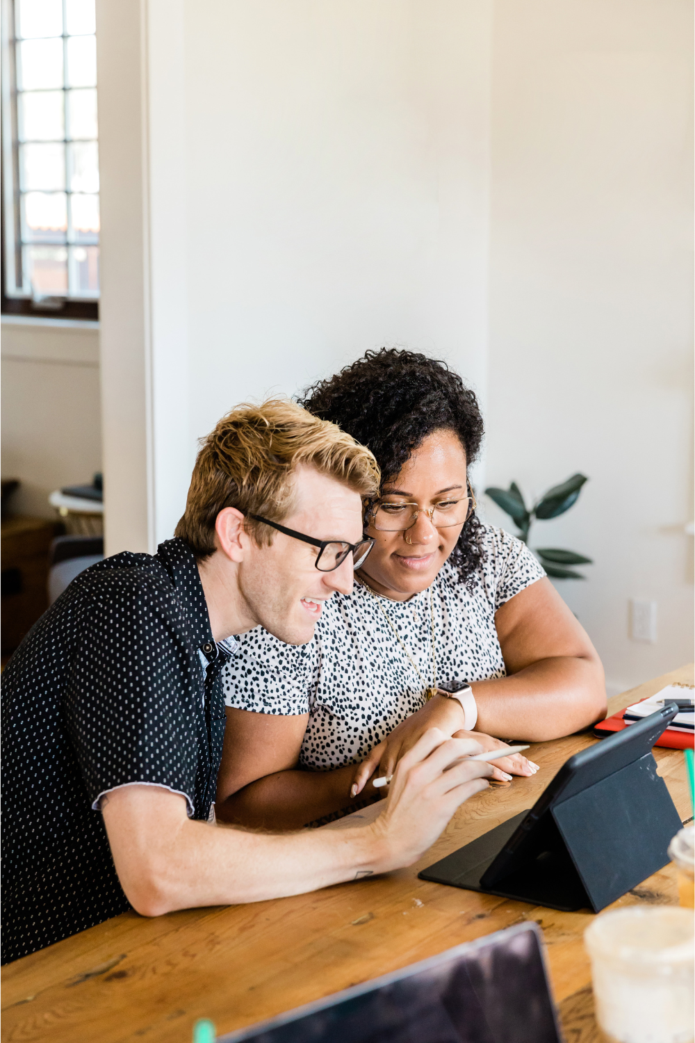 Two people sitting at a table looking at a tablet screen.