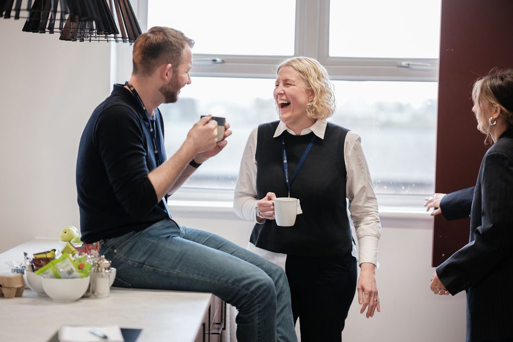 team sat in office, laughing together.