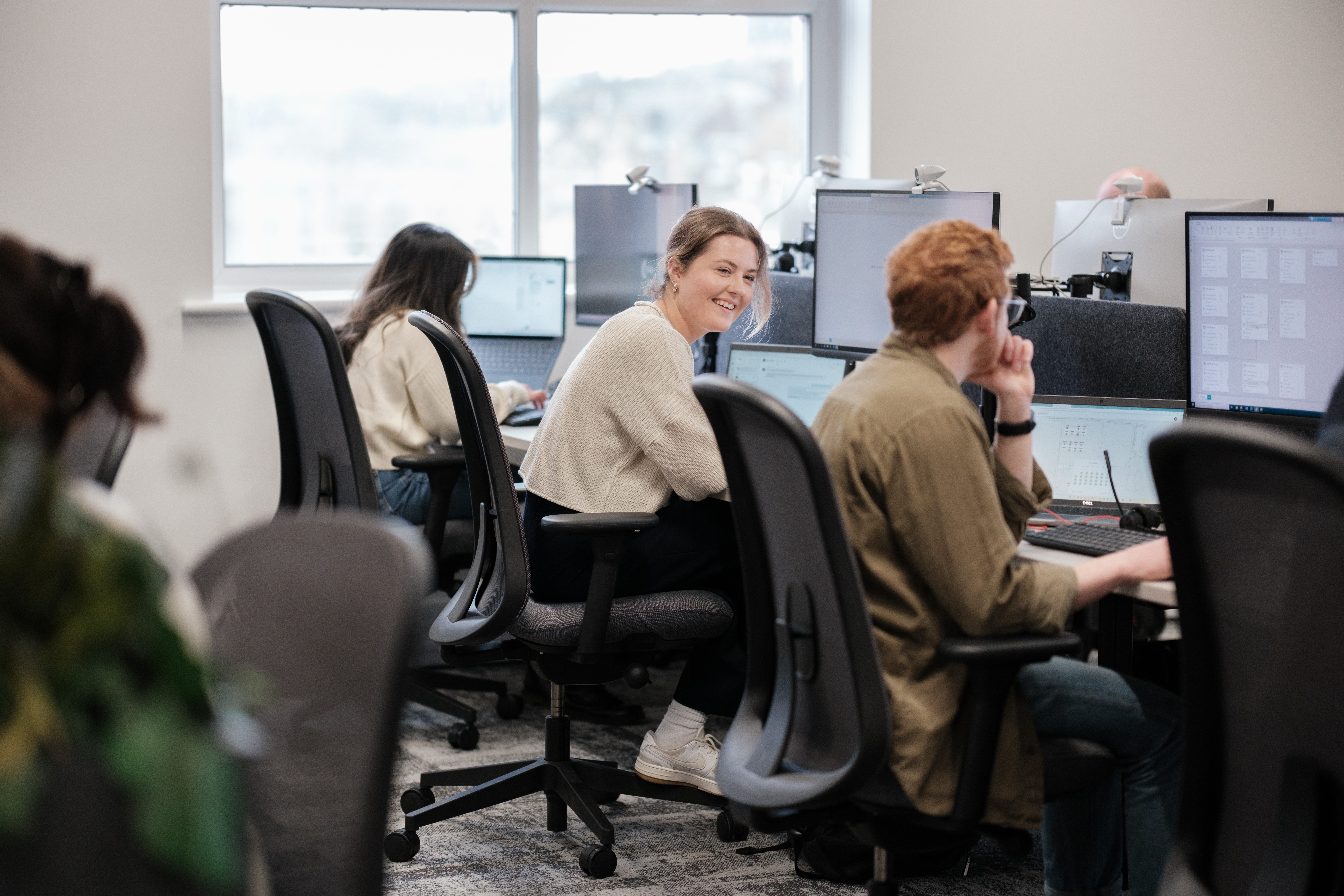 team members sat together at their desks talking and laughing