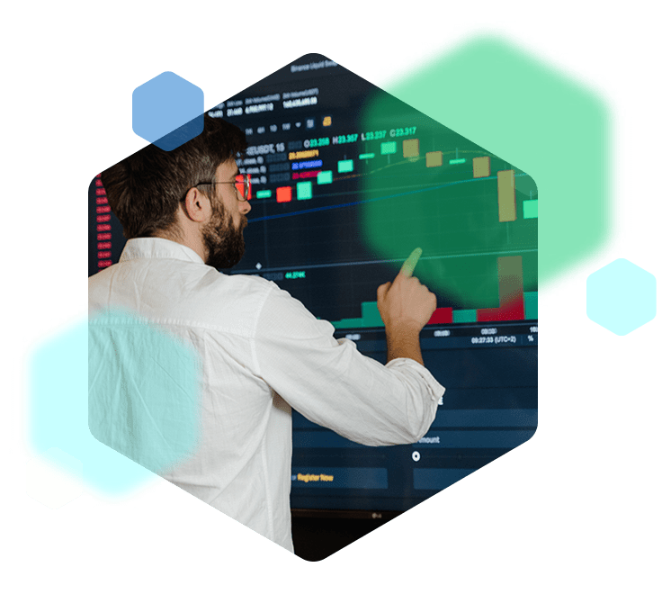 An employee standing in front of a large screen, pointing at colourful graphs displayed.
