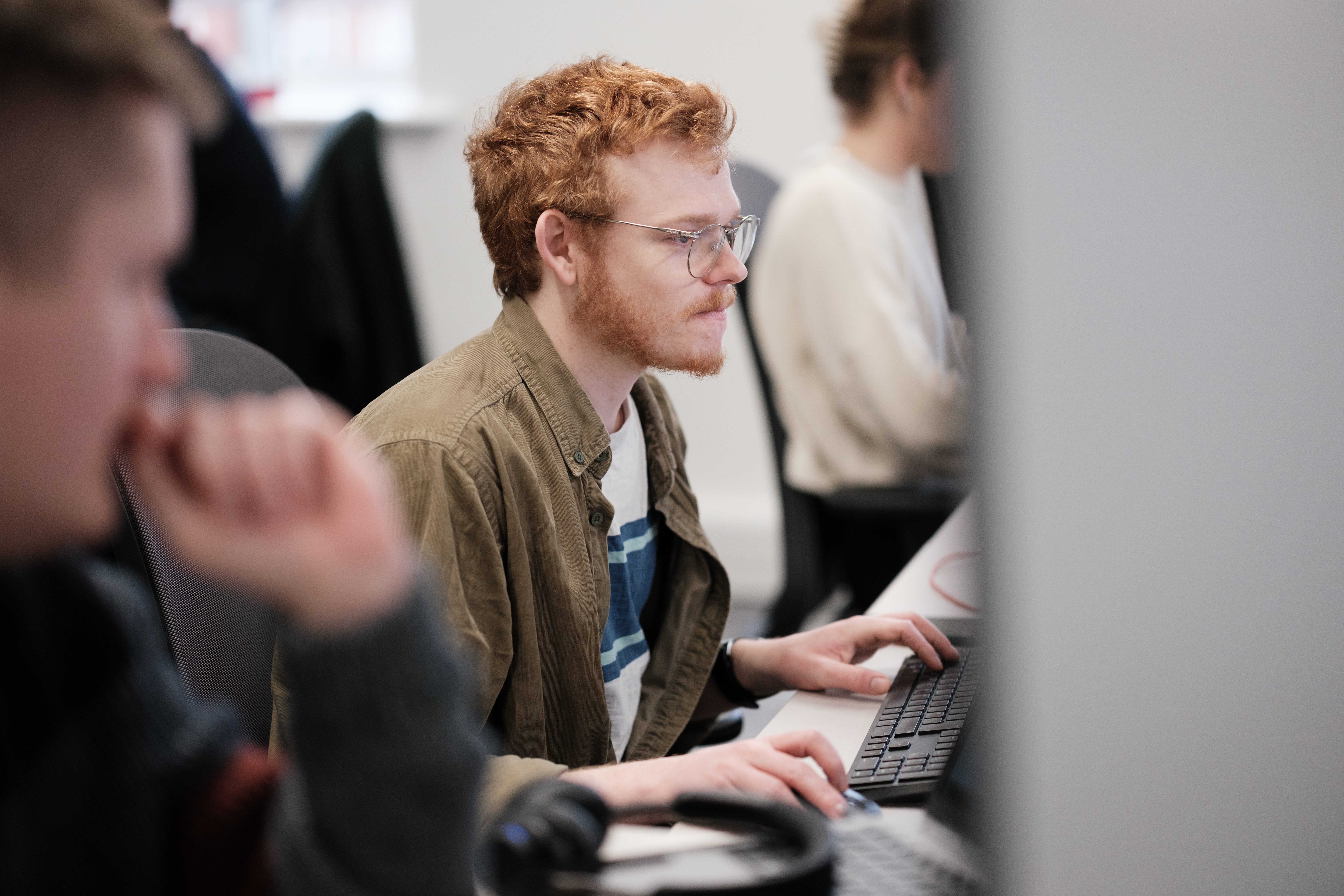 A young Simpson Associates Consultant in the office working at AI solutions at the computer.